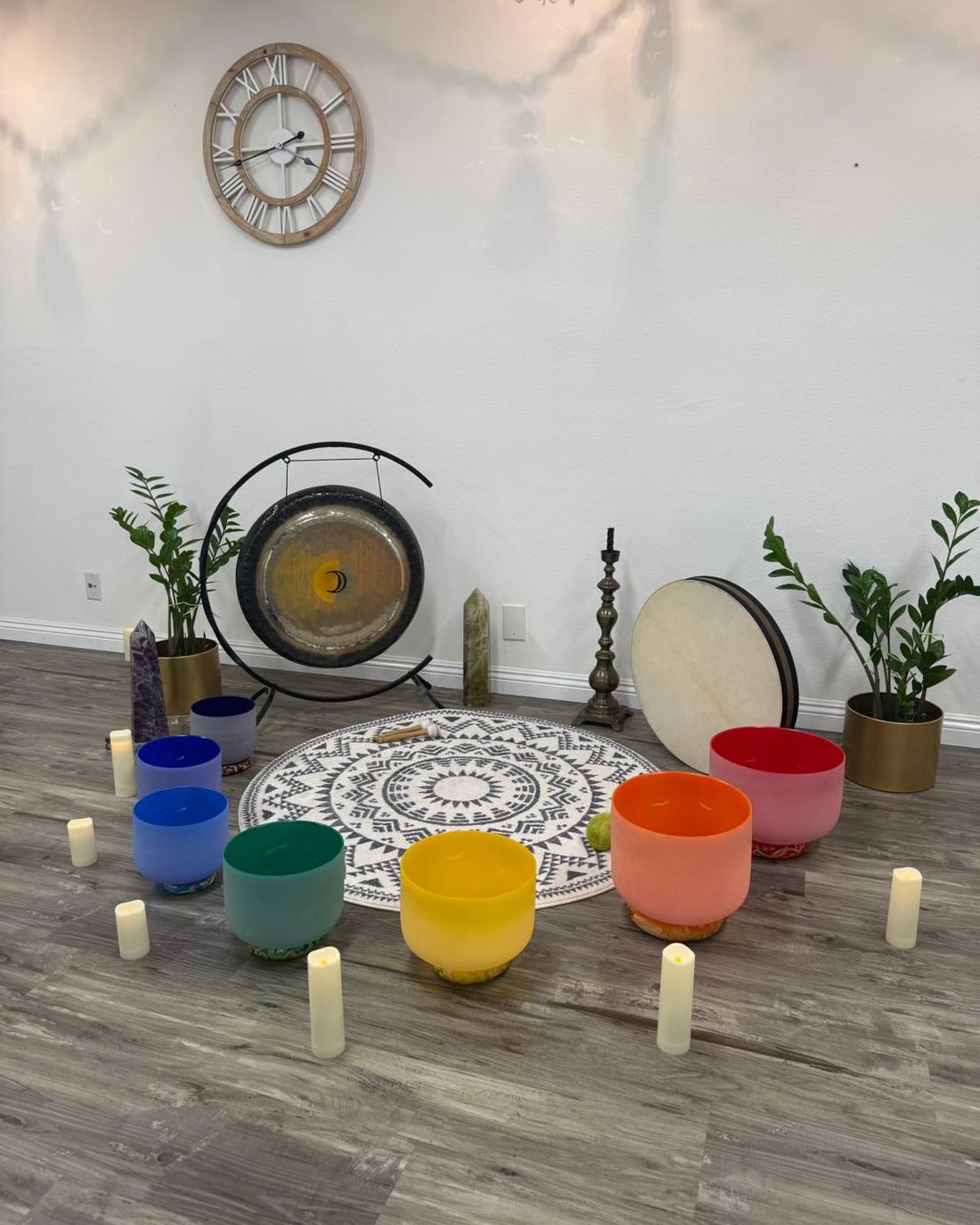 The gong, drum and chakra bowls arranged on the mandala rug against a white wall