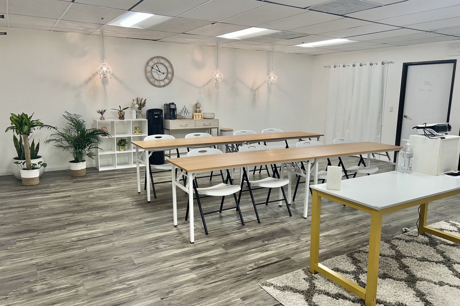 The studio arranged classroom-style with long tables, chairs, plants and pendant lighting