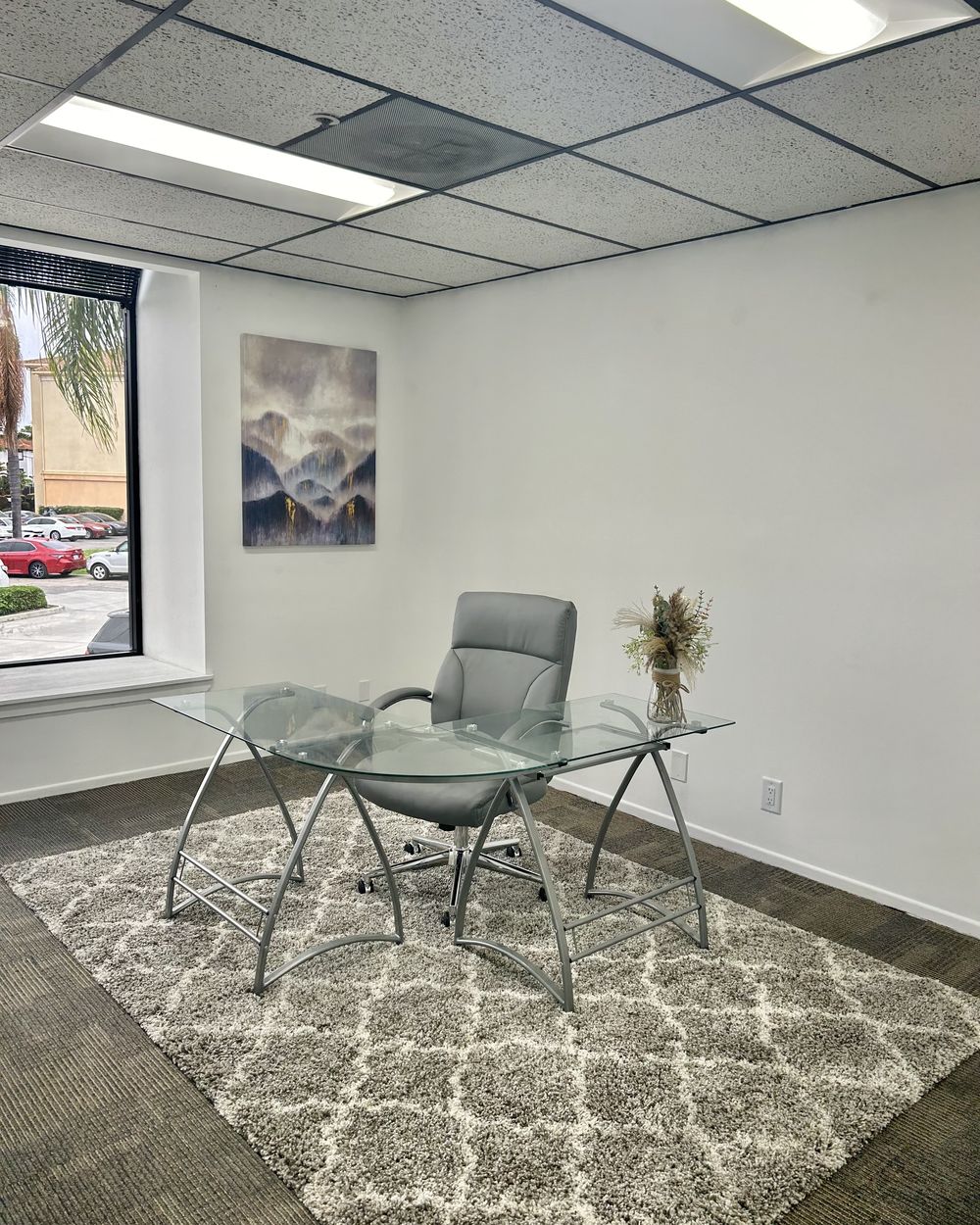 The side office off the studio with a desk, chair, window and artwork
